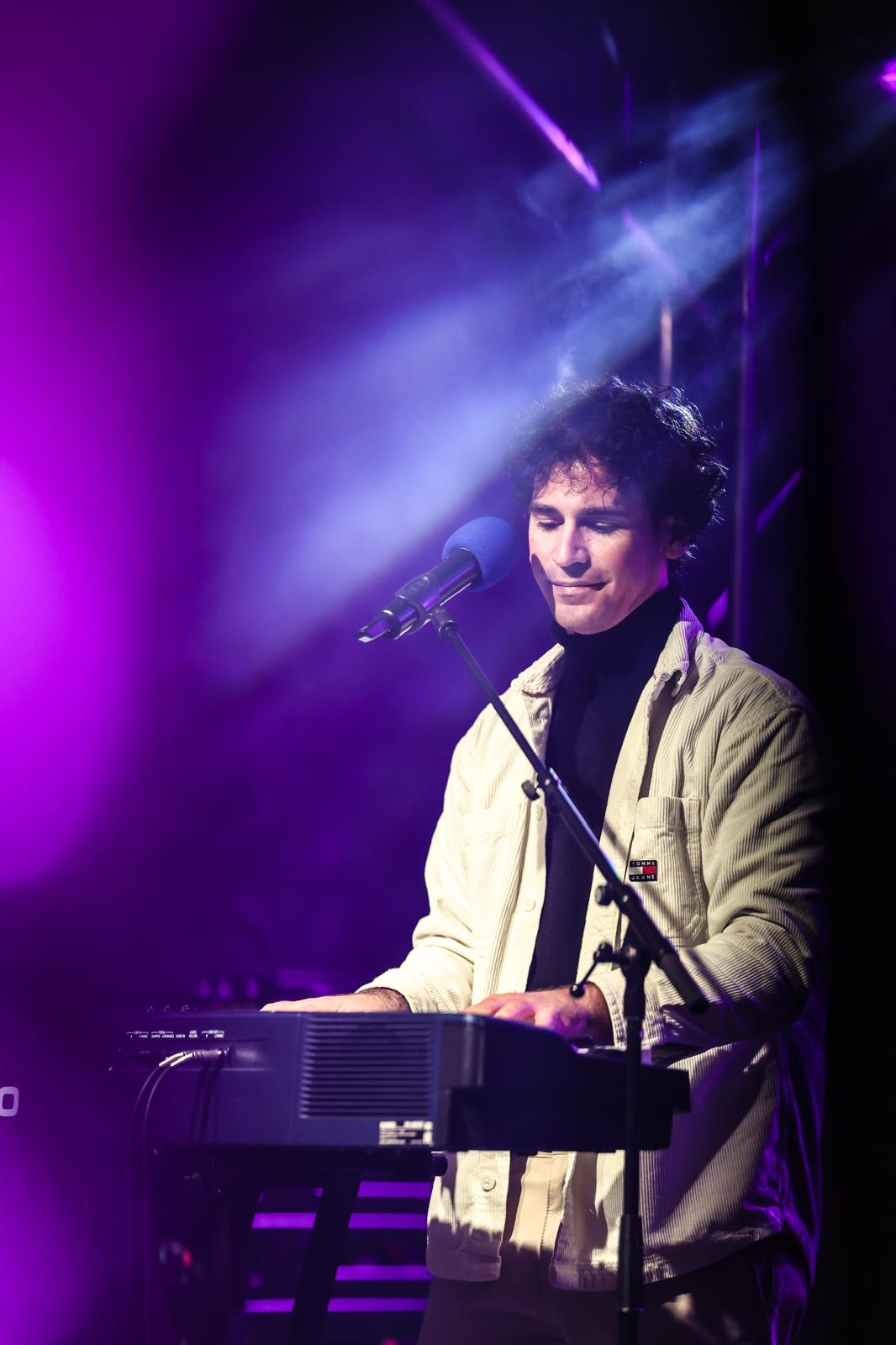 Salvatore De Concilis performing at the piano under purple stage lights